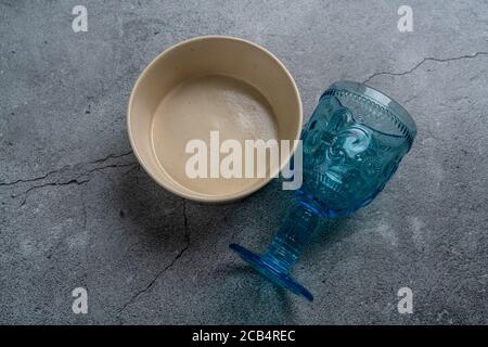 Tableware and decorations for serving a festive table. Plates, wine glasses and cutlery with gray decorative textile on white background. Stock Photo