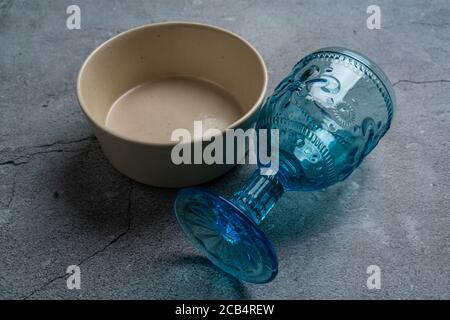 Tableware and decorations for serving a festive table. Plates, wine glasses and cutlery with gray decorative textile on white background. Stock Photo