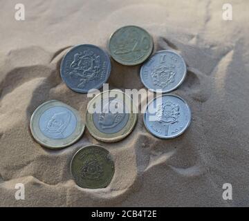 Closeup shot of various different coins on sand Stock Photo