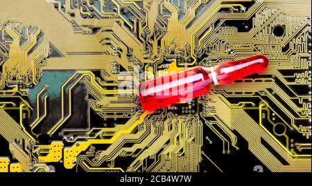 glass ampoule with a red vaccine on a dark circuit board of a microcircuit with contact tracks concept on theme of vaccination of chipping and chipiza Stock Photo
