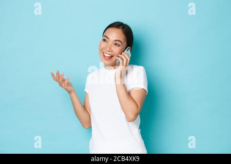 Lifestyle, people and beauty concept. Young attractive asain girl discussing something, having cheerful conversation, talking on mobile phone and Stock Photo