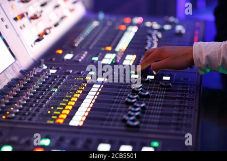 Sound engineer working with controls of a sound mixing console. Selective focus. Stock Photo
