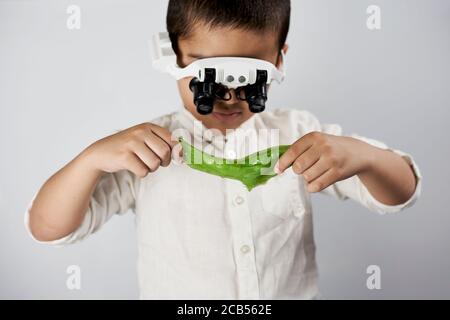 Schoolboy equipped with headband magnifying glass conducting scientific experiments at the workshop Stock Photo