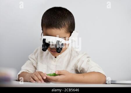 A little smart boy discovering the micro world with headband magnifying glass Stock Photo