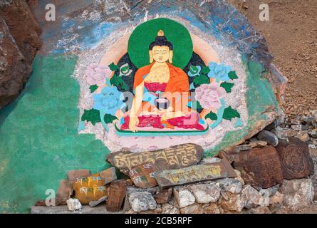 Rock painting of Buddha in a lotus position at the entrance to the ancient Buddhist Key Gompa monastery; prayer Buddhist mantras engraved on the stone Stock Photo