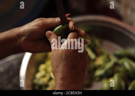 Indian Mother Cutting Green Vegetables with Sharp Edge Knife Close up Stock Photo