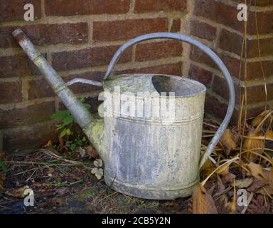 close up old rusty tin watering can in cemetery wall Stock Photo