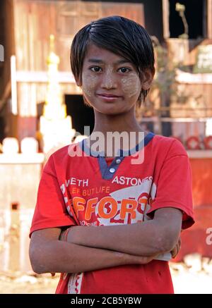 Mandalay, Myanmar - January 31, 2010: close up portrait of unidentified young woman with tanaka paste on her face on a city street on a sunny day Stock Photo