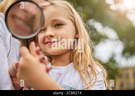 Woman showing for little girl how work with glass magnifying Stock Photo