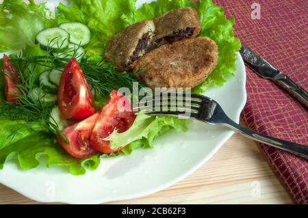 portion of potato cutlets on a plate with vegetables (cucumber, tomato) and greens (lettuce, dill) Stock Photo