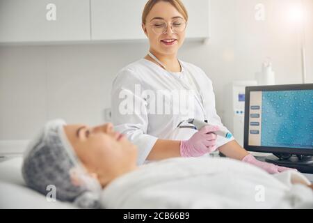 Beautician sitting by her client during the cosmetic procedure Stock Photo