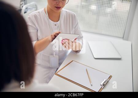 Dark-haired patient sitting in front of a dermatologist Stock Photo
