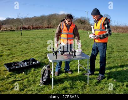 Two men prepare to fly a drone with a camera in a countryside garden in the Cotswolds Stock Photo