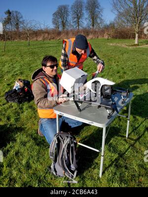 Two men preparing to fly a drone with a camera in a countryside garden in the Cotswolds Stock Photo