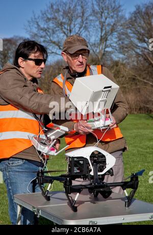 Two photographers prepare to  fly a drone with a camera in a Cotsold garden Stock Photo