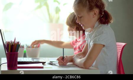 Cute children use laptop for education, online study, home studying, Boy and Girl have homework at distance learning. Lifestyle concept for home schooling. Stock Photo