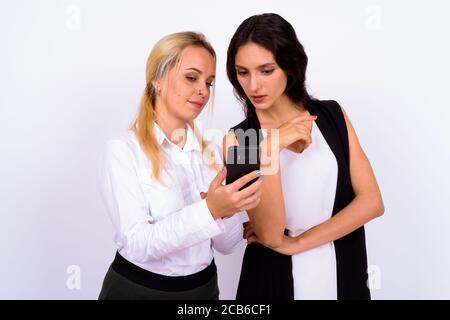 Portrait of two young beautiful businesswomen using phone together
