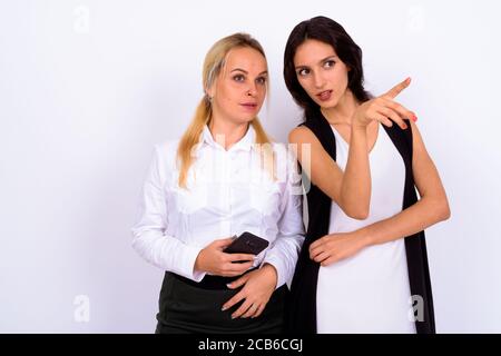 Portrait of two young beautiful businesswomen using phone together