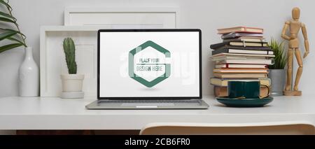 Close up view of study table with mock up laptop, stack of books and decorations on white table Stock Photo