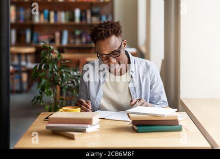 Happy black guy studying or working with books at coffee shop Stock Photo