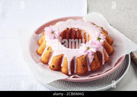 Festive Bundt cake with pink glaze, decorated with cherry flowers. Stock Photo