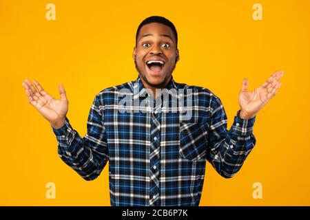 Surprised African Guy Posing With Opened Mouth Over Yellow Background Stock Photo