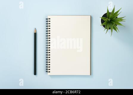 Spiral Notebook or Spring Notebook in Unlined Type and Office Plant and Pencil on Blue Pastel Minimalist Background Stock Photo