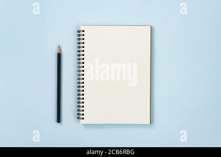 Spiral Notebook or Spring Notebook in Unlined Type and Pencil on Blue Pastel Minimalist Background Stock Photo