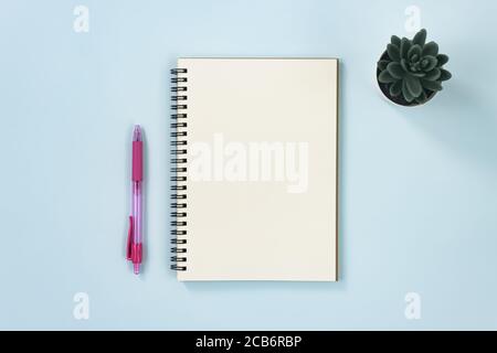 Spiral Notebook or Spring Notebook in Unlined Type and Pen and Office Plant on Blue Pastel Minimalist Background Stock Photo