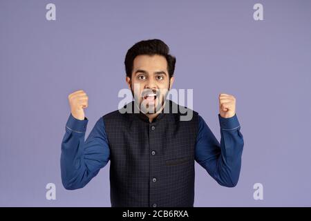 Victory and achievement. Excited Indian man gesturing YES on violet background Stock Photo