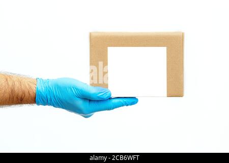 Men's hand holding cardboard boxes. Delivery by courier in medical gloves. The shipping time during coronavirus. Quarantine  Stock Photo