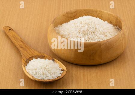 Jasmine rice filled in a wooden bowl and in a wooden spoon on wooden table Stock Photo