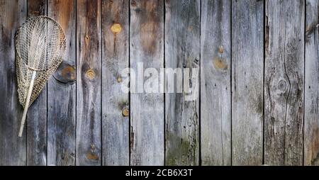 barnwood sign with fishing net Fishing concept. Old fisherman equipment on vintage wooden background with  copyspace. Landing net hooked on rustic board Stock Photo