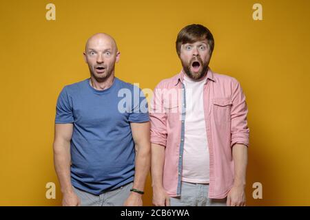 Two surprised men open their mouths in shock and stand in dumbfounded looking at the camera.  Stock Photo