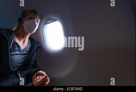 Caucasian Woman wearing face mask during her flight in a plane Stock Photo
