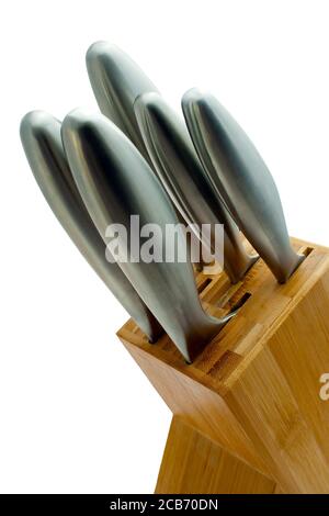 Stainless steel knives close cropped in a light wood block on an isolated white background Stock Photo