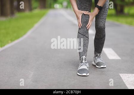 Knee Trauma. Unrecognizable Woman Jogger Hut Her Leg During Running Outdoors Stock Photo