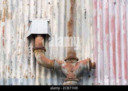Peeling and faded paint work on an old corrugated iron wall with parallel vertical lines Stock Photo