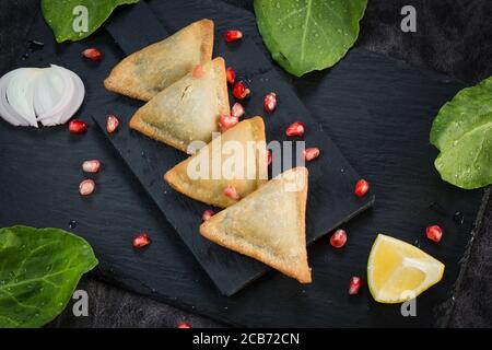 Veg Samosa - is a crispy and spicy Indian triangle shape snack which has crisp outer layer of maida filling of mashed potato, peas and spices. Served Stock Photo