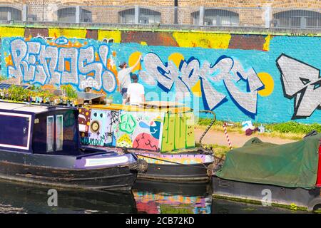 England London Stratford Park Hackney Wick graffiti man men painting letters wall towpath Stock Photo