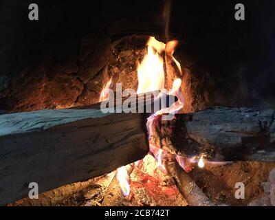 Traditional way of making food by using fire wood as bio fuel on open fire in old kitchen in a village. Rural kitchen using bio wood fuel for cooking. Stock Photo