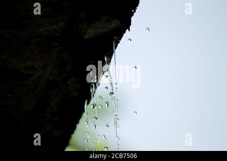 Closeup shot of rain flowing down from a roof down Stock Photo