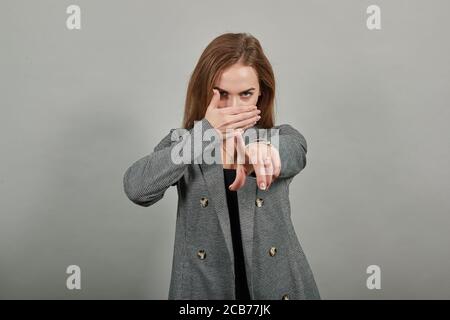 Hand pointer with forefinger pointing forward. Index finger to show direction. Means choosing, introducing too. Indicating towards. Young attractive woman, dressed gray jacket, with green eyes Stock Photo