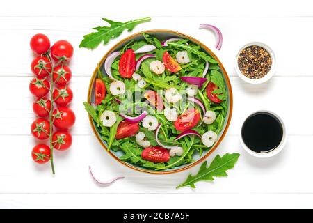 Mediterranean diet menu concept Healthy salad of fresh vegetables - tomatoes, arugula, purple onions, shrimps, soy sauce and sesame seeds in plate on Stock Photo