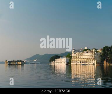 Lake Pichola with old buildings and ruins in the middle distance and Aravalli hills on horizon at sunrise in Udaipur, Rajasthan, India. Stock Photo