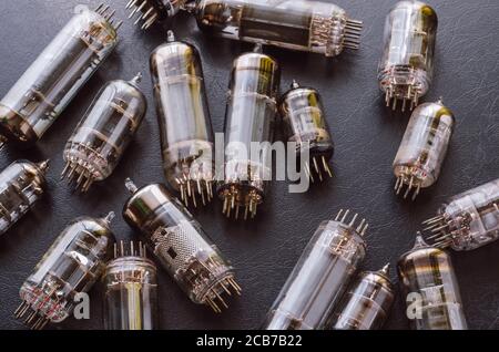 Random vacuum tubes on a black background. A group of radio tubes of different sizes and purposes. Selective focus. Stock Photo