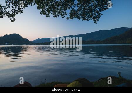 Early morning lake Bled in Slovenia. Calm lake, rising sun behind the mountains, Alps. Sleeping bags in the foreground, Outdoor Adventure in the Trigl Stock Photo
