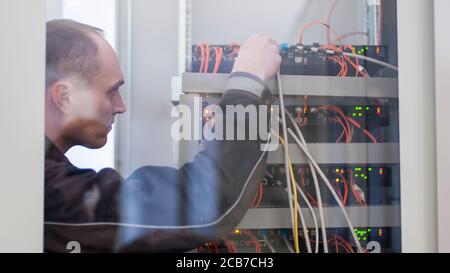 Electrician engineer tests electrical installations and wires on relay protection system. Bay control unit. Medium voltage switchgear Stock Photo