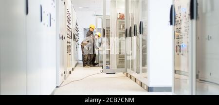 Field service crew testing electronics or inspecting electrical installation system. Bay control unit. Medium voltage switchgear Stock Photo