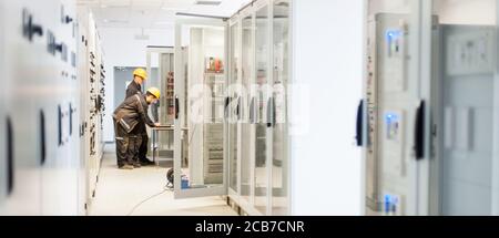 Field service crew testing electronics or inspecting electrical installation system. Bay control unit. Medium voltage switchgear Stock Photo